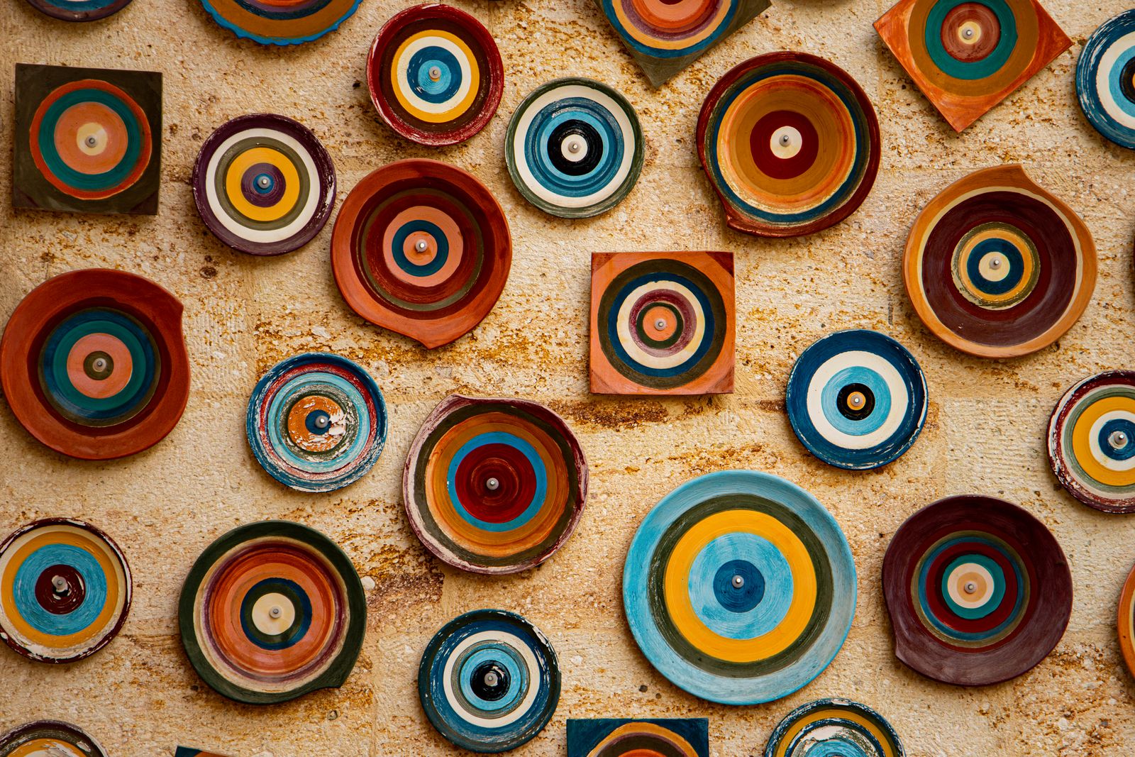 Hand-painted ceramic plates displayed on a stone wall in Avanos